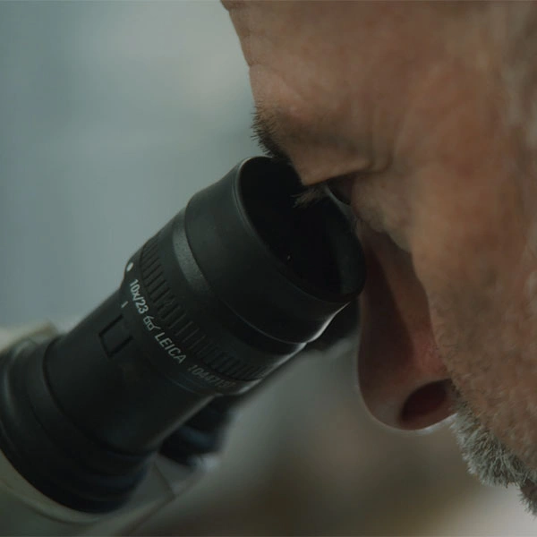 Un professionnel inspecte une pièce de mécanique de précision avec un microscope.