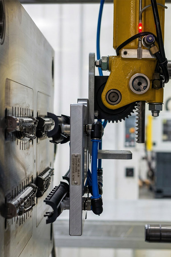 After the product has been injected into the mould and sufficiently cooled, a robot removes the parts from the mould and places them on a conveyor belt.