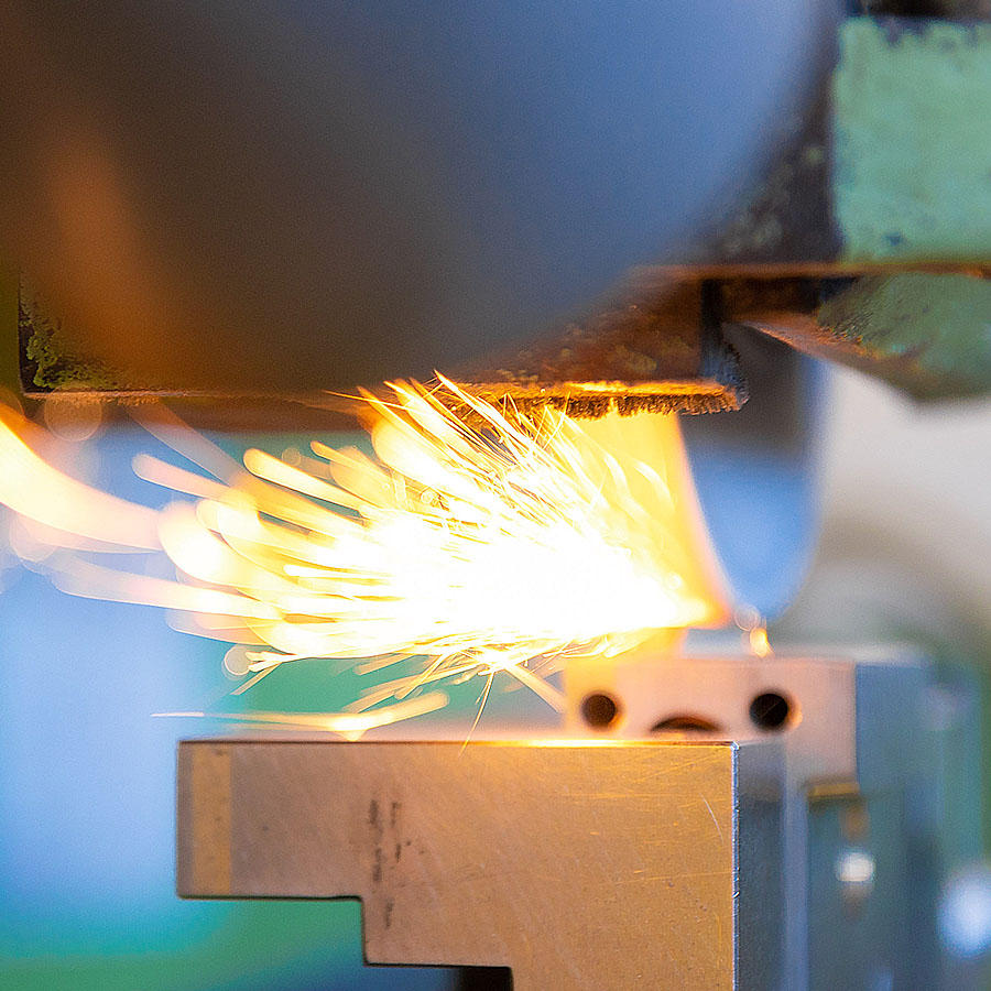 Gros plan de la machine au moment où la meule commence à rectifier une pièce de précision et où les étincelles jaillissent dans le sens de rotation de la meule.